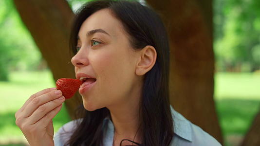 年轻妇女在野餐时吃草莓视频的预览图