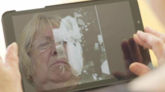 高级女性在平板电脑上看旧照片视频的预览图