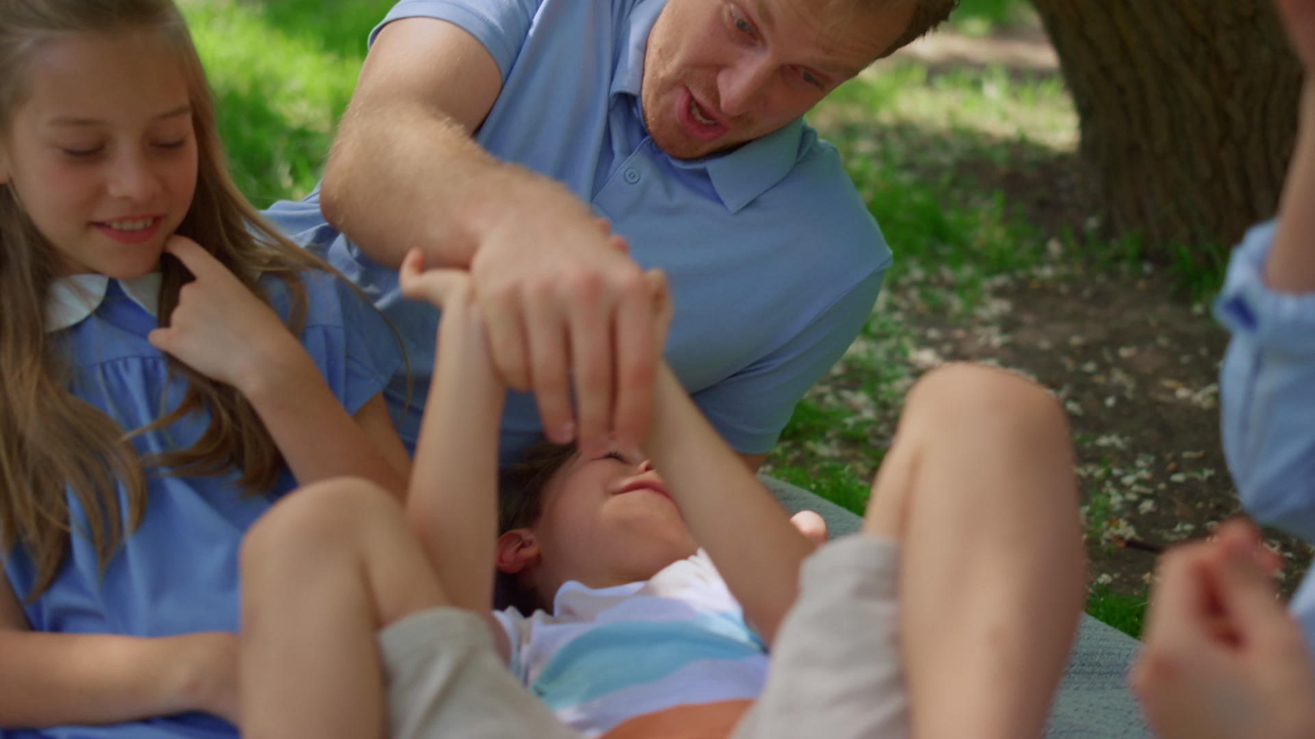 笑着父亲在野餐毯特写镜头上挠痒痒的儿子视频的预览图