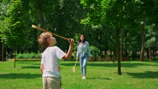 快乐的母亲和儿子在公园里打羽毛球视频的预览图