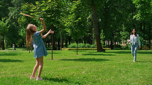 一个开朗的女孩在公园里和妈妈打羽毛球视频的预览图