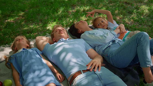 幸福的家庭放松躺在野餐毯上视频的预览图