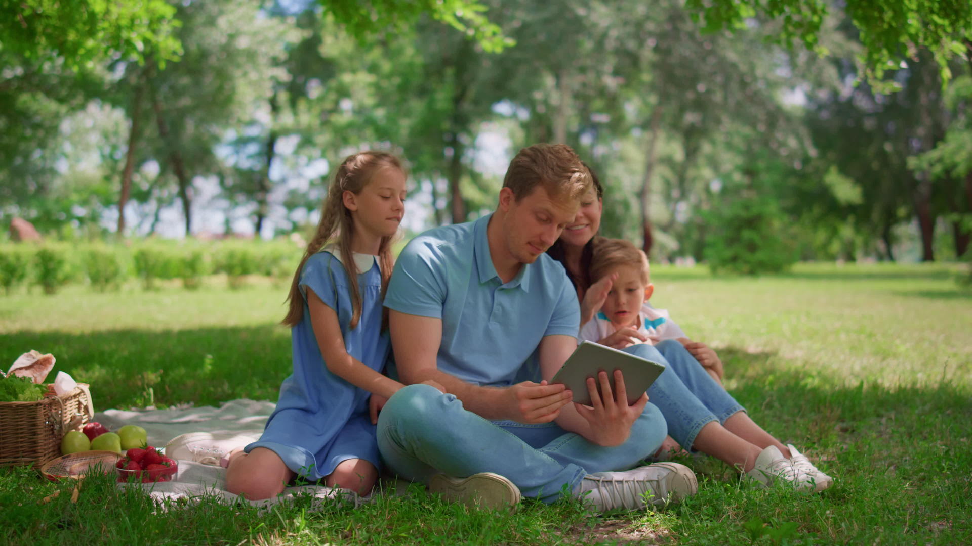 一个年轻的家庭坐在阳光明媚的公园里视频的预览图
