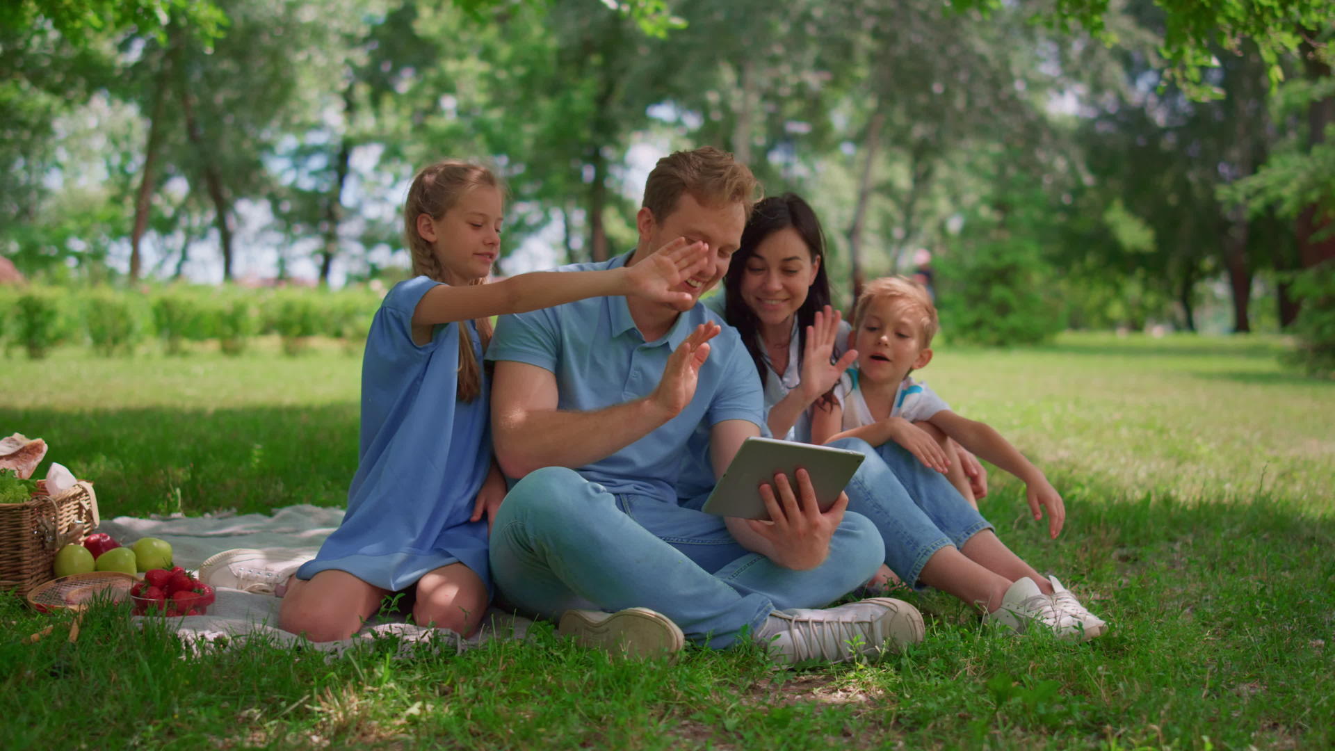 微笑的家人在夏天挥手用平板电脑在大自然中交流视频的预览图