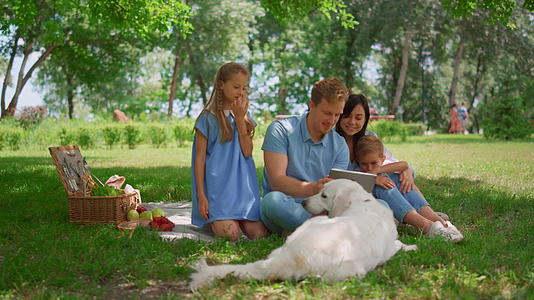 快乐的家庭在野餐时使用平板电脑视频的预览图