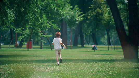 阳光明媚的日子里精力充沛的小男孩在郁郁葱葱的田野里奔跑视频的预览图