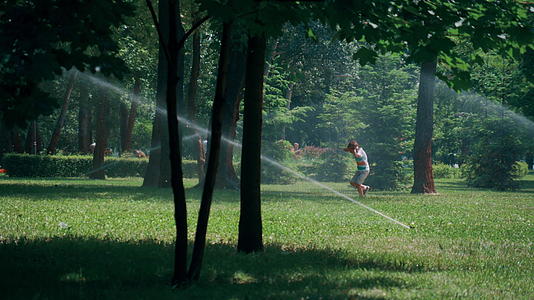 小男孩自来水洒在绿色公园里耳朵不会溅起来视频的预览图