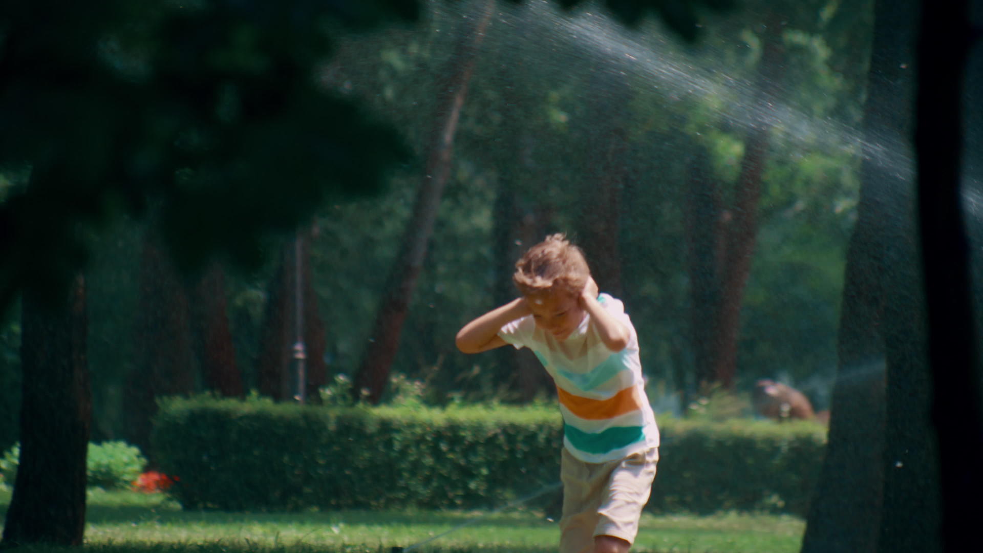快乐的孩子们在阳光明媚的公园里跑步时洒水遮住耳朵视频的预览图