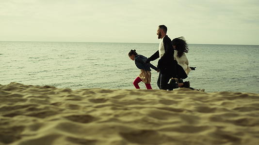 玩耍的家庭在沙滩上奔跑视频的预览图