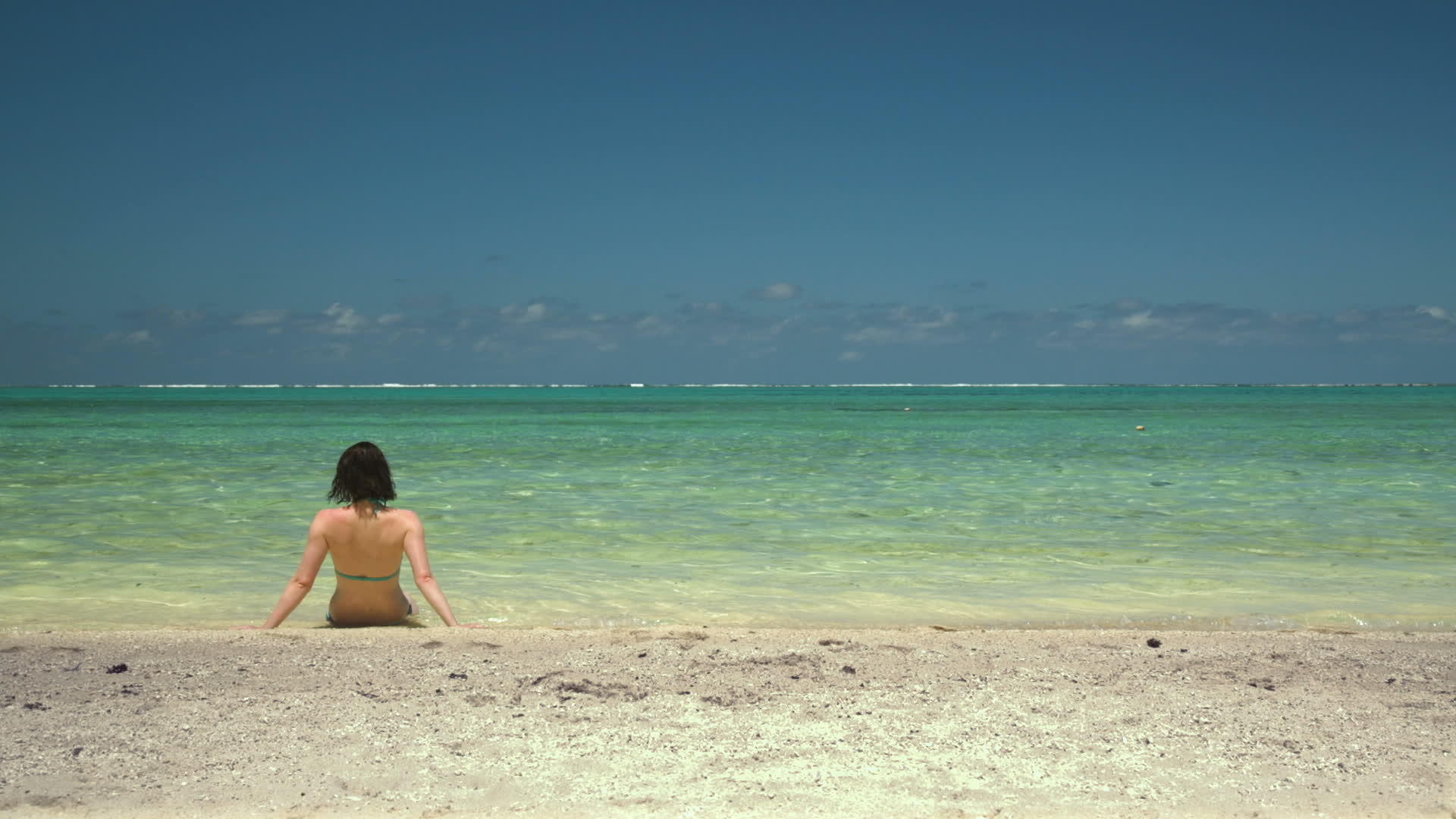 坐在水边的年轻女性坐在热带沙滩上视频的预览图