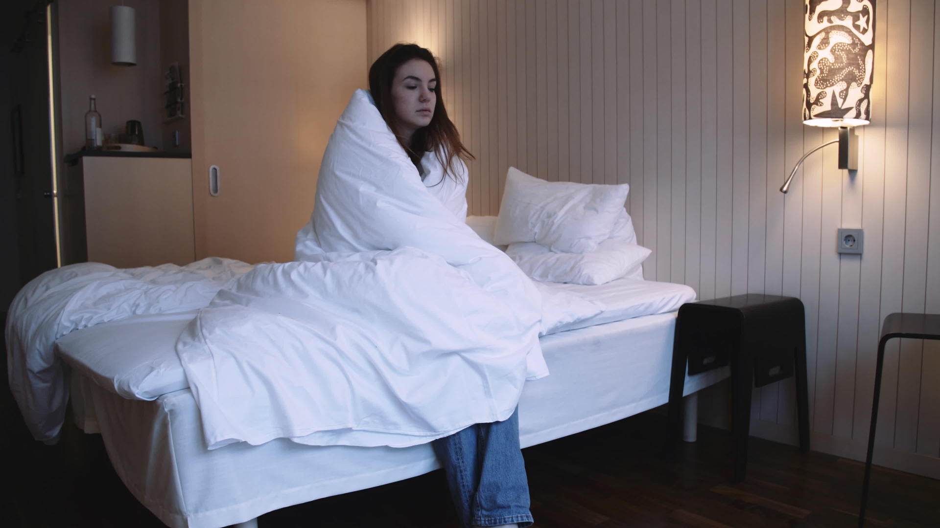 坐在床上的年轻女士被毯子裹在床上视频的预览图