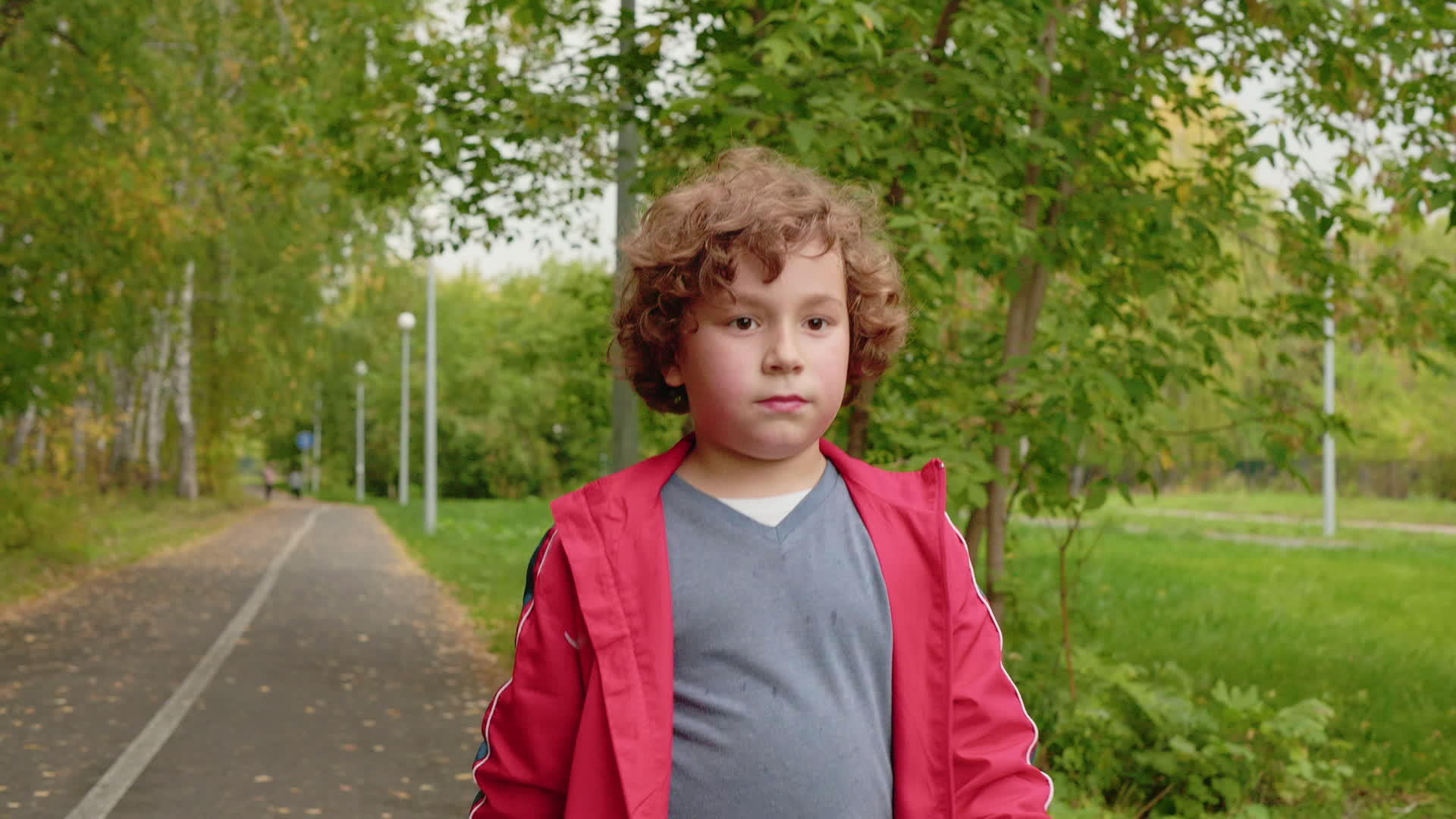 一个年轻的卷发男孩在夏天的公园里走来走去像一个十几岁的男孩视频的预览图