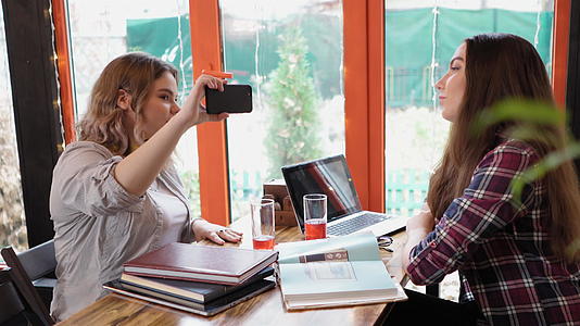 两个女朋友一起在咖啡店学习咖啡和笔记本电脑视频的预览图