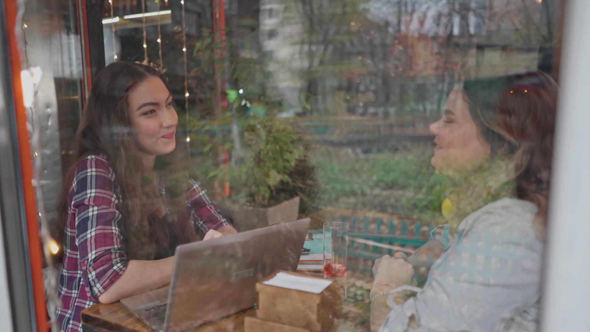 透过玻璃两名女学生在咖啡店喝咖啡聊天视频的预览图