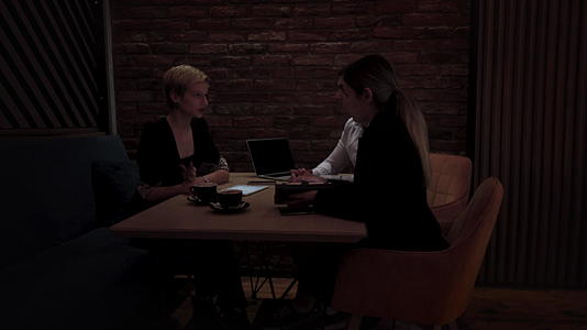 深夜在一家现代咖啡馆开会下班后三位年轻的商业同事视频的预览图