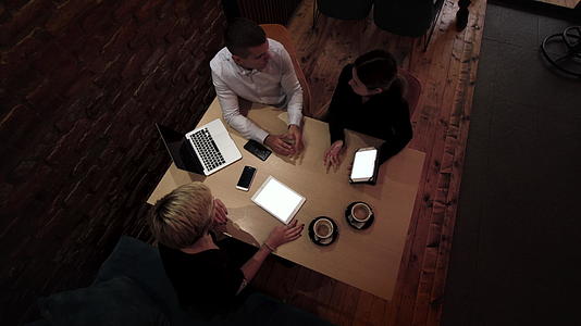 深夜三位年轻的商业同事在一家现代咖啡馆开会视频的预览图