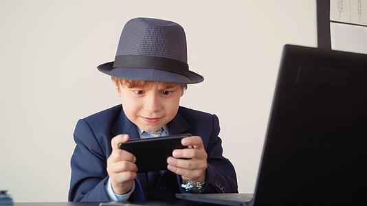 年轻的商人在商务办公室的工作场所玩手机游戏小男孩穿着衣服视频的预览图