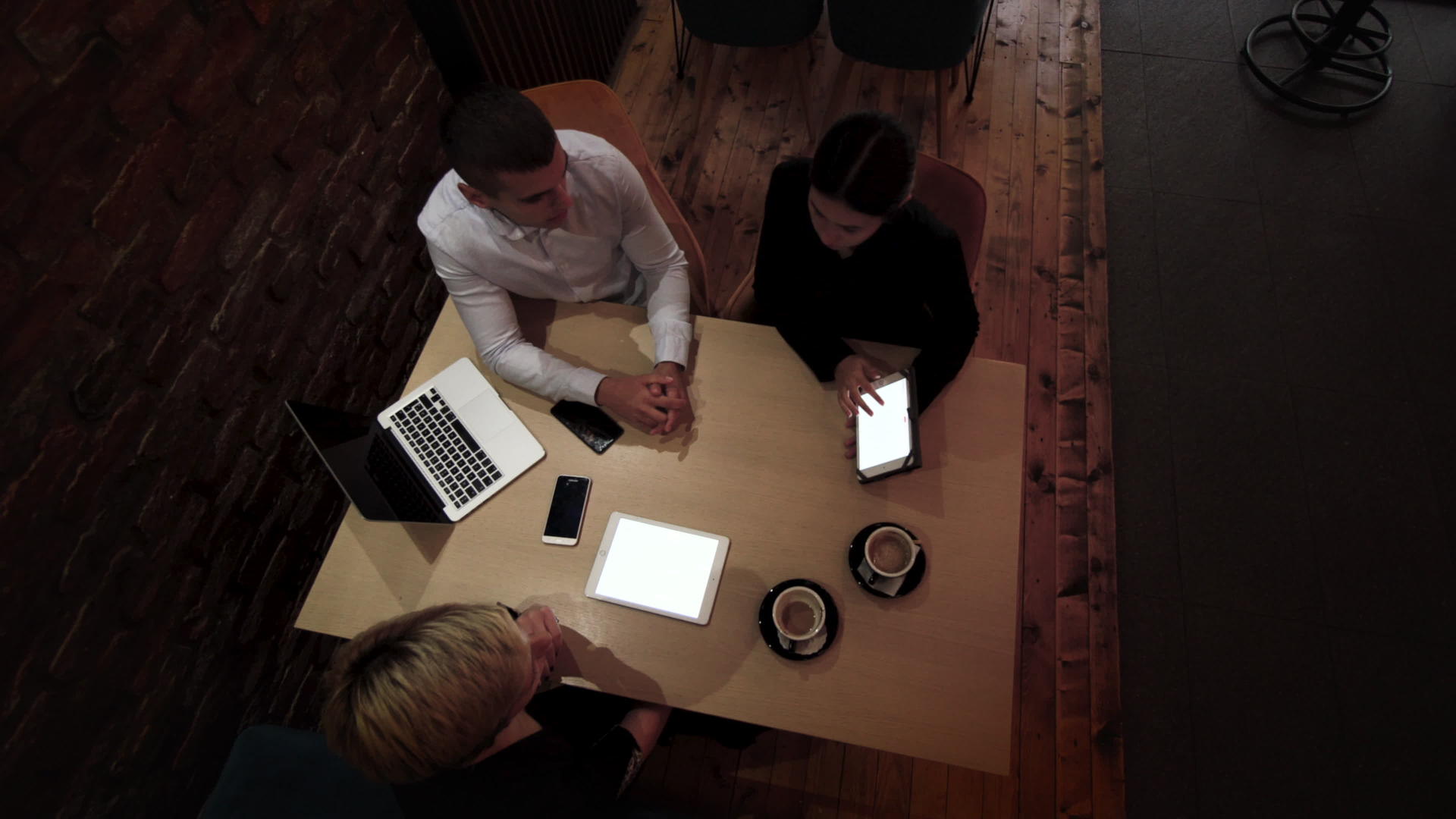 深夜三位年轻的商业同事在一家现代咖啡馆开会下班视频的预览图