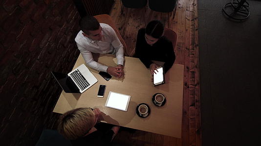 深夜三位年轻的商业同事在一家现代咖啡馆开会下班视频的预览图