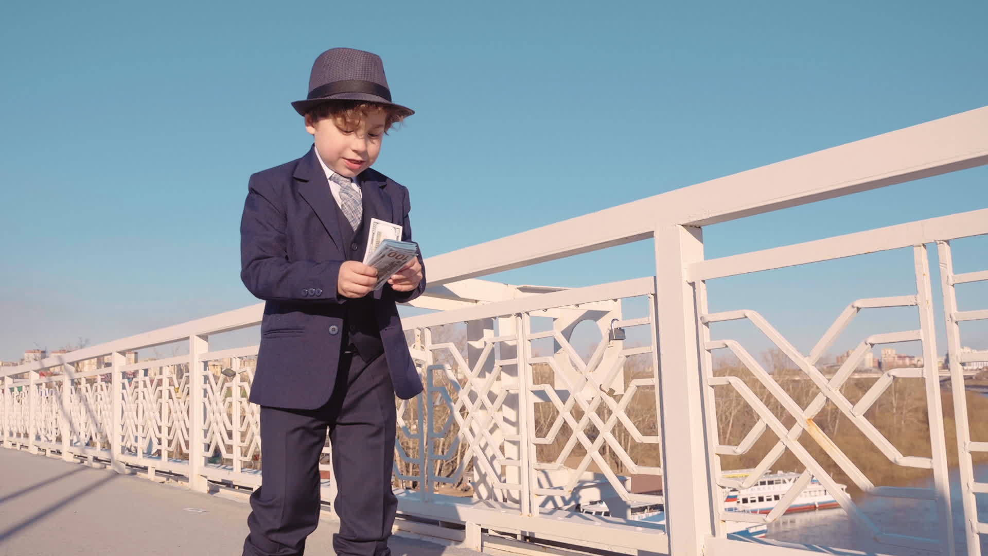 年轻商人男孩穿着黑色西装 戴着帽子 从桥上扔钱视频的预览图