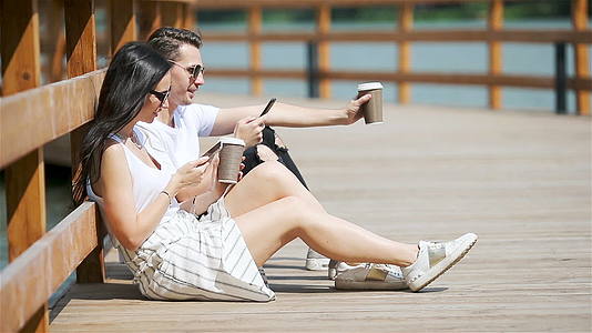 一对快乐的夫妇在公园里使用智能手机视频的预览图