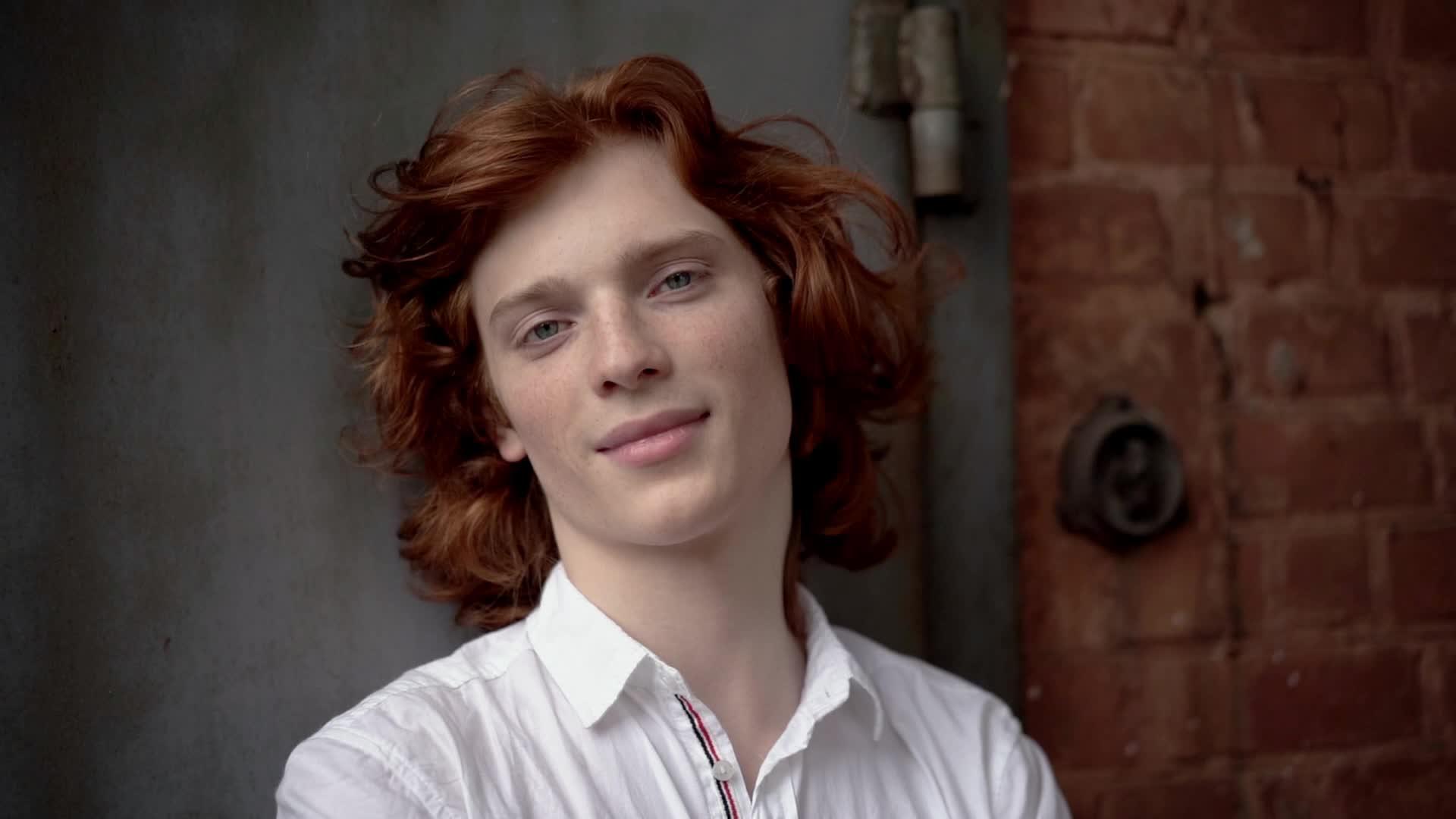 红头发的年轻人穿着白衬衫在街上摆姿势视频的预览图