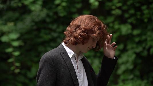 穿着西装和长发的红发男子在花园里穿着西装视频的预览图