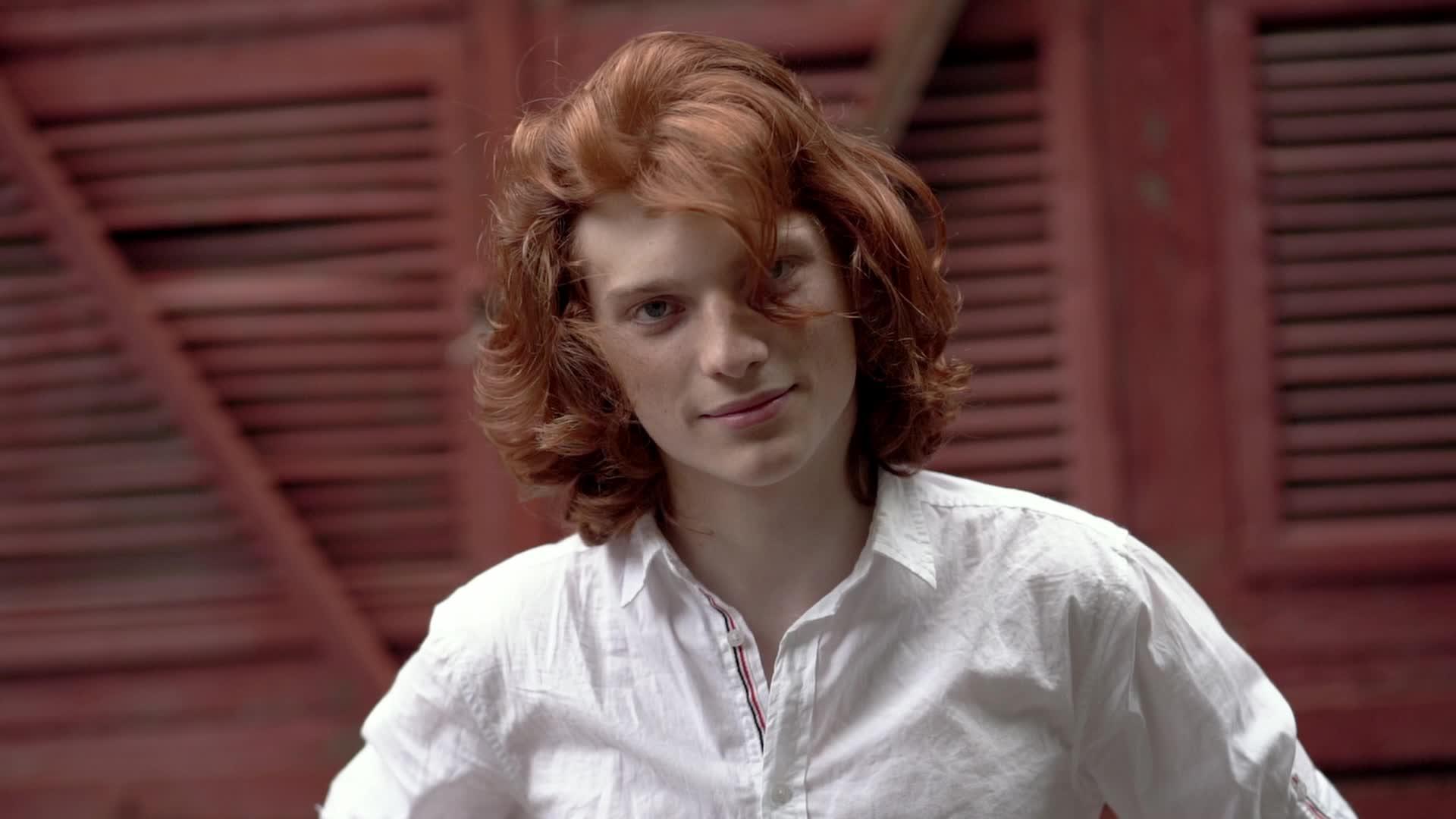 红头发的年轻人穿着白衬衫在街上摆姿势视频的预览图