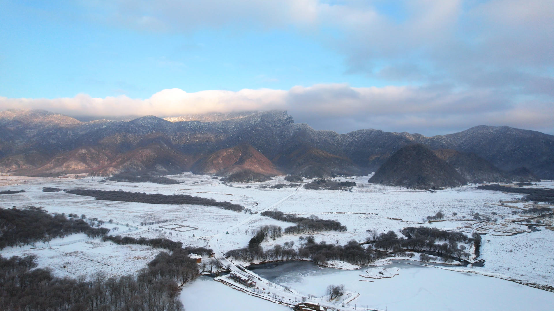 航拍冬天雪景湖北神农架大九湖上积雪结冰的湖面和蓝天白云山峰4k素材视频的预览图