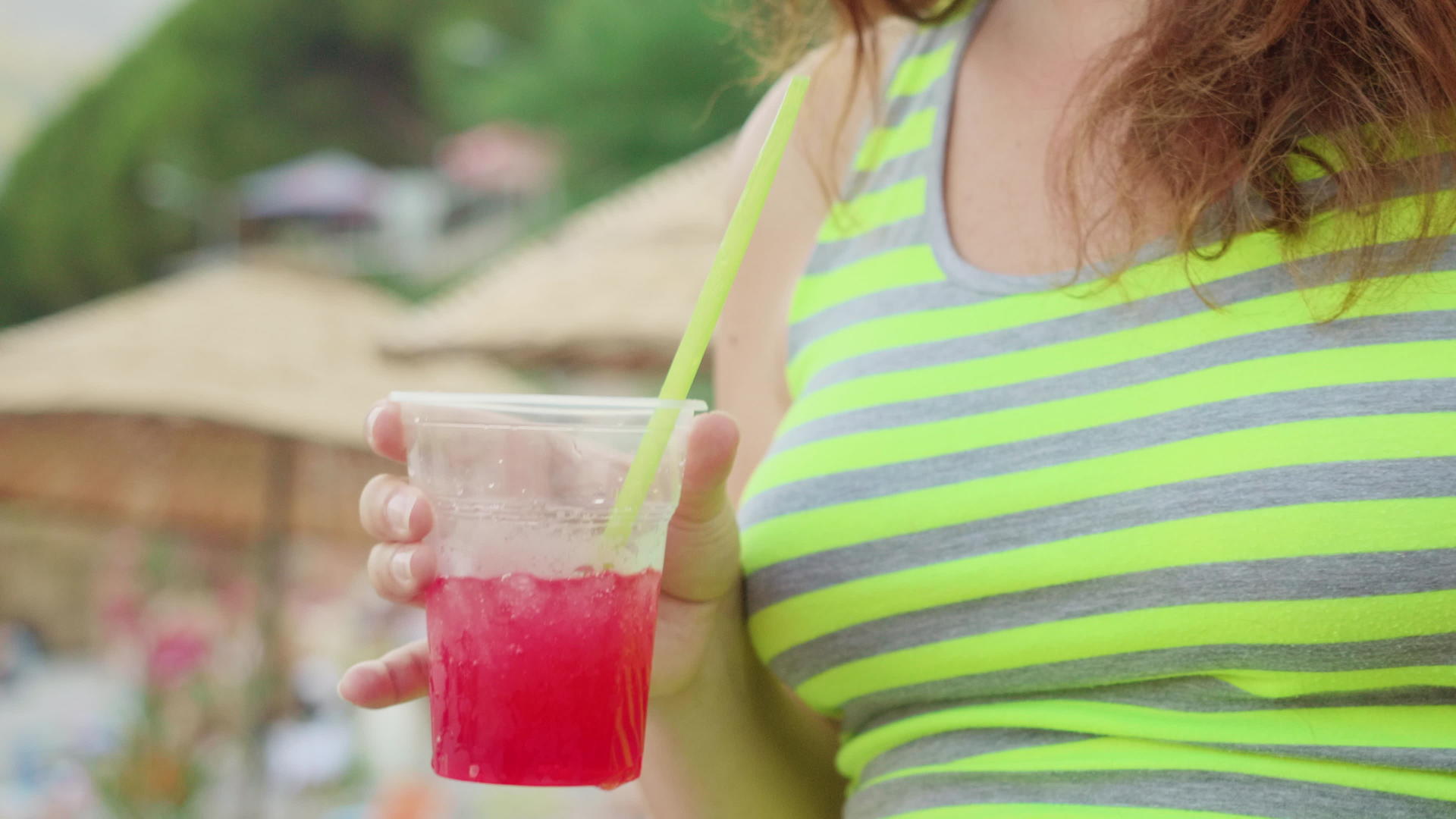 在阳光明媚的日子里女孩拿着红鸡尾酒和冰块视频的预览图