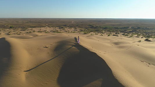 孤独的年轻女子穿着白色裙子留着长发在沙漠中视频的预览图