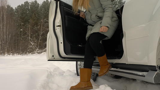 这位年轻的女司机从冬季森林风景的停车场开车出来视频的预览图