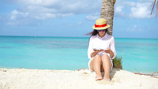 在热带白色沙滩期间年轻女读书视频的预览图