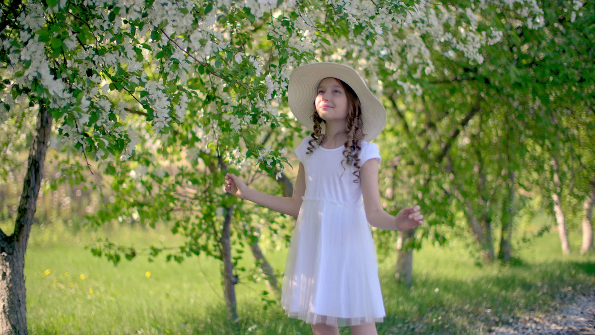 在阳光明媚的春天年轻女孩享受着开花的果园视频的预览图