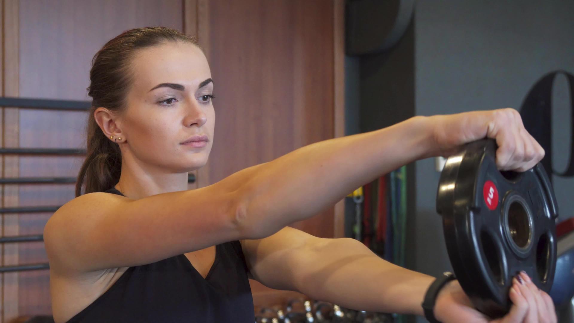年轻女孩在健身房用特殊的圆发哑巴做运动视频的预览图