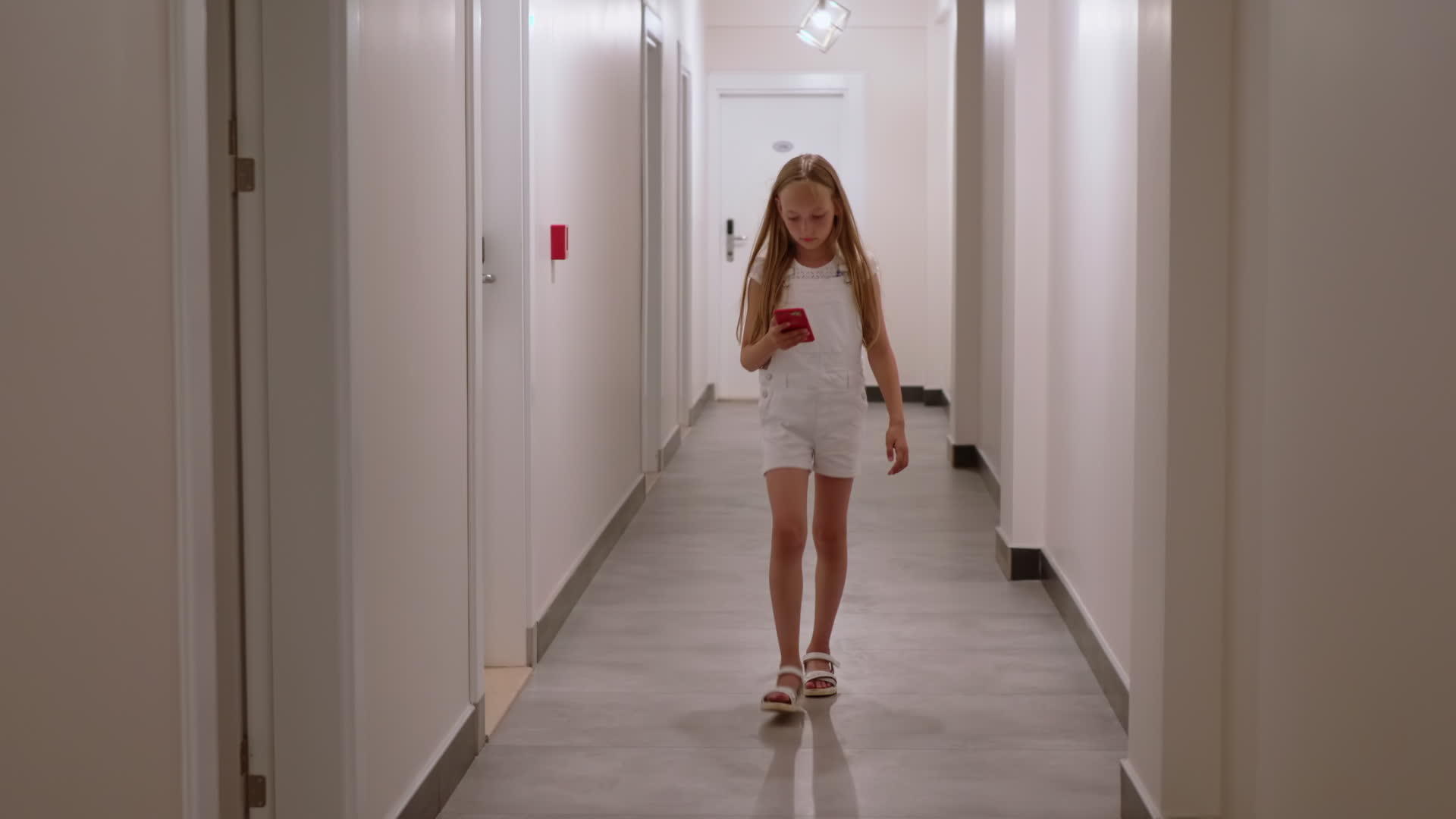 走在酒店走廊里的年轻女孩和十几岁的手机女孩在长长的酒店里视频的预览图