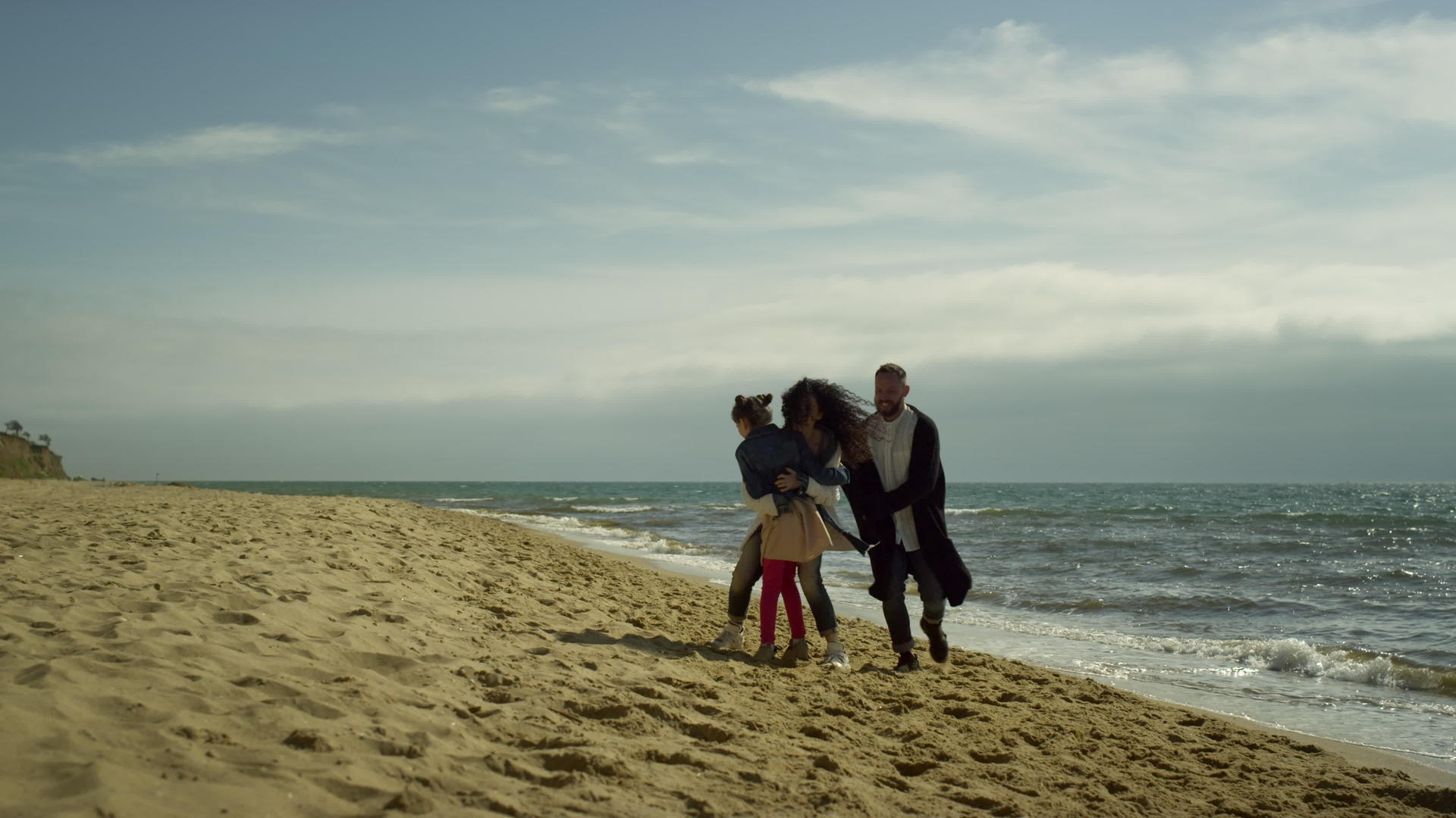 一个可爱的家庭在沙滩上拥抱在一起视频的预览图