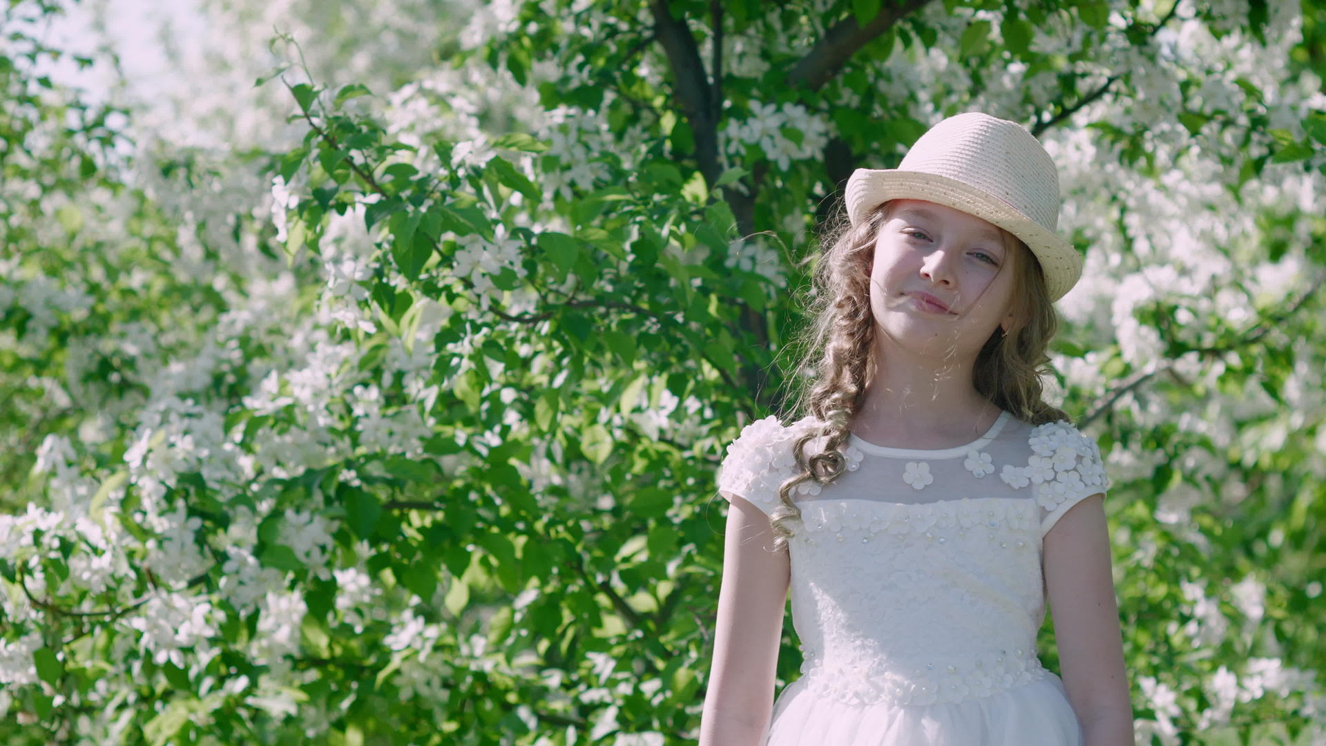 年轻女孩在阳光明媚的花园里穿着白色连衣裙和草帽视频的预览图