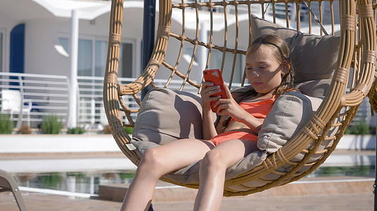 在度假酒店的吊椅茧中寻找移动的年轻女孩女孩在度假视频的预览图