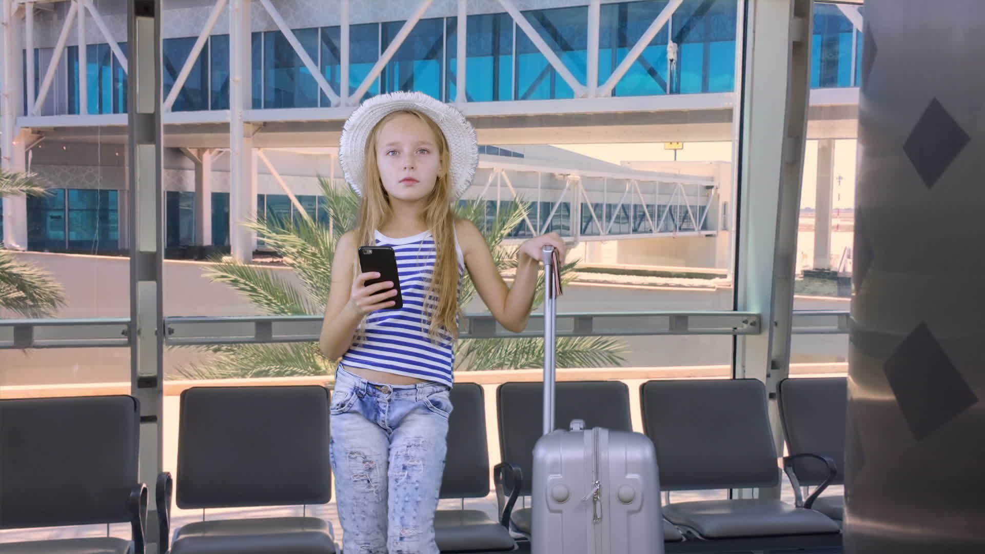 带着手机和手提箱在机场休息室等候的年轻女性视频的预览图