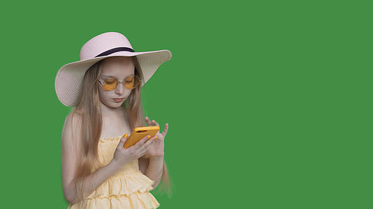 穿着黄色连衣裙和太阳镜的年轻女孩穿着透明的绿色背景视频的预览图