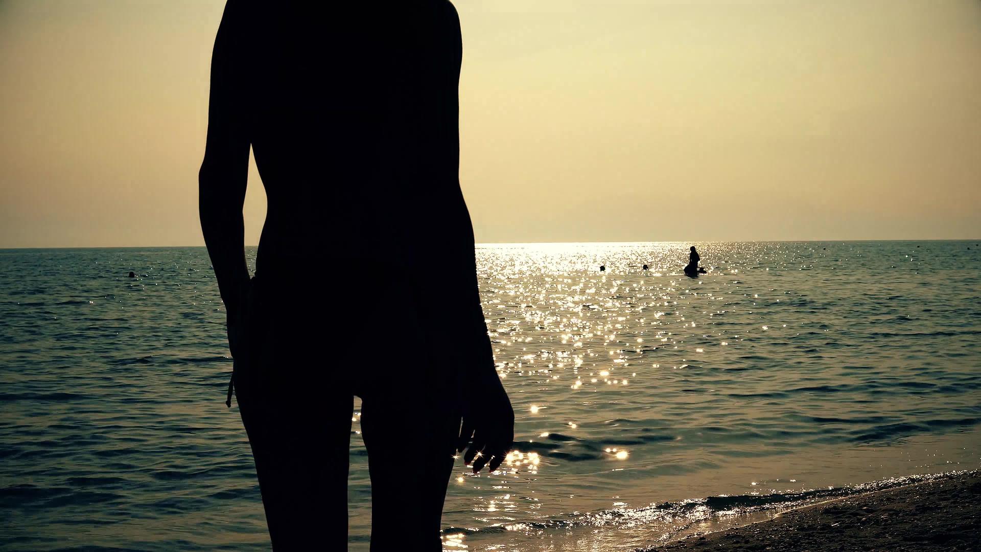 日出日落时在海边散步的冲浪女孩视频的预览图