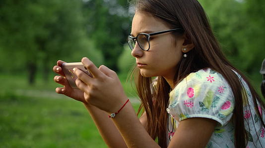 女孩在绿林里用手机发短信视频的预览图