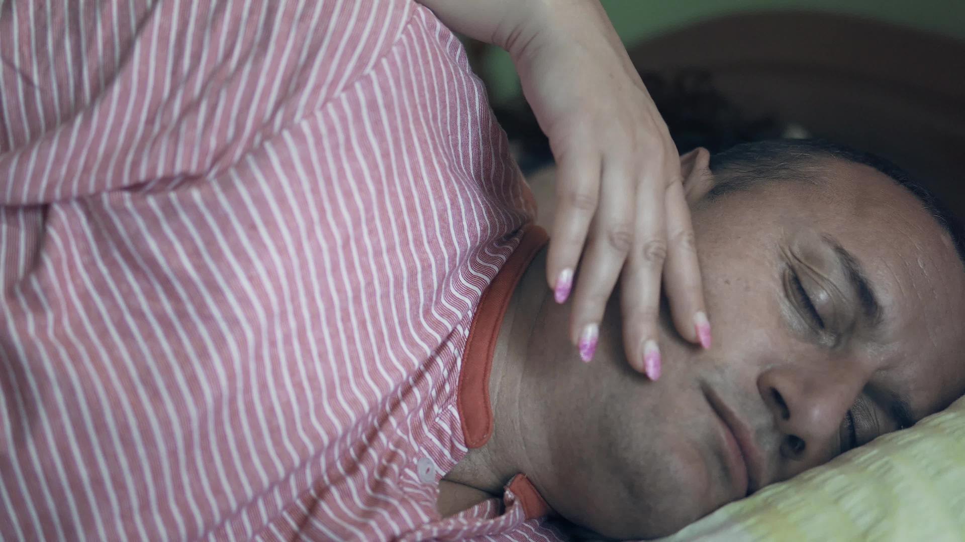 当一个年轻的女人浪漫地醒来时一个沉睡的男人用手触摸着视频的预览图
