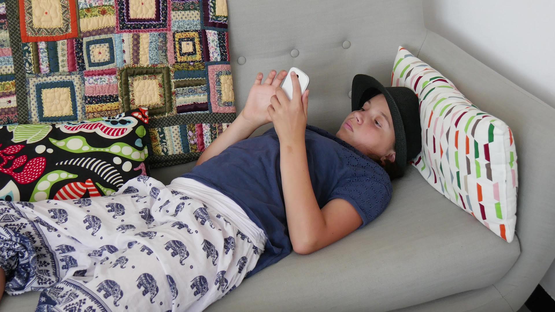 青少年用智能手机躺在沙发上视频的预览图