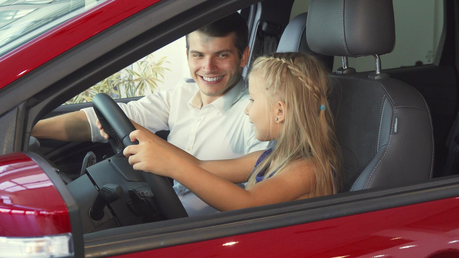 一个小女孩和她父亲坐在车里假装转动方向盘视频的预览图