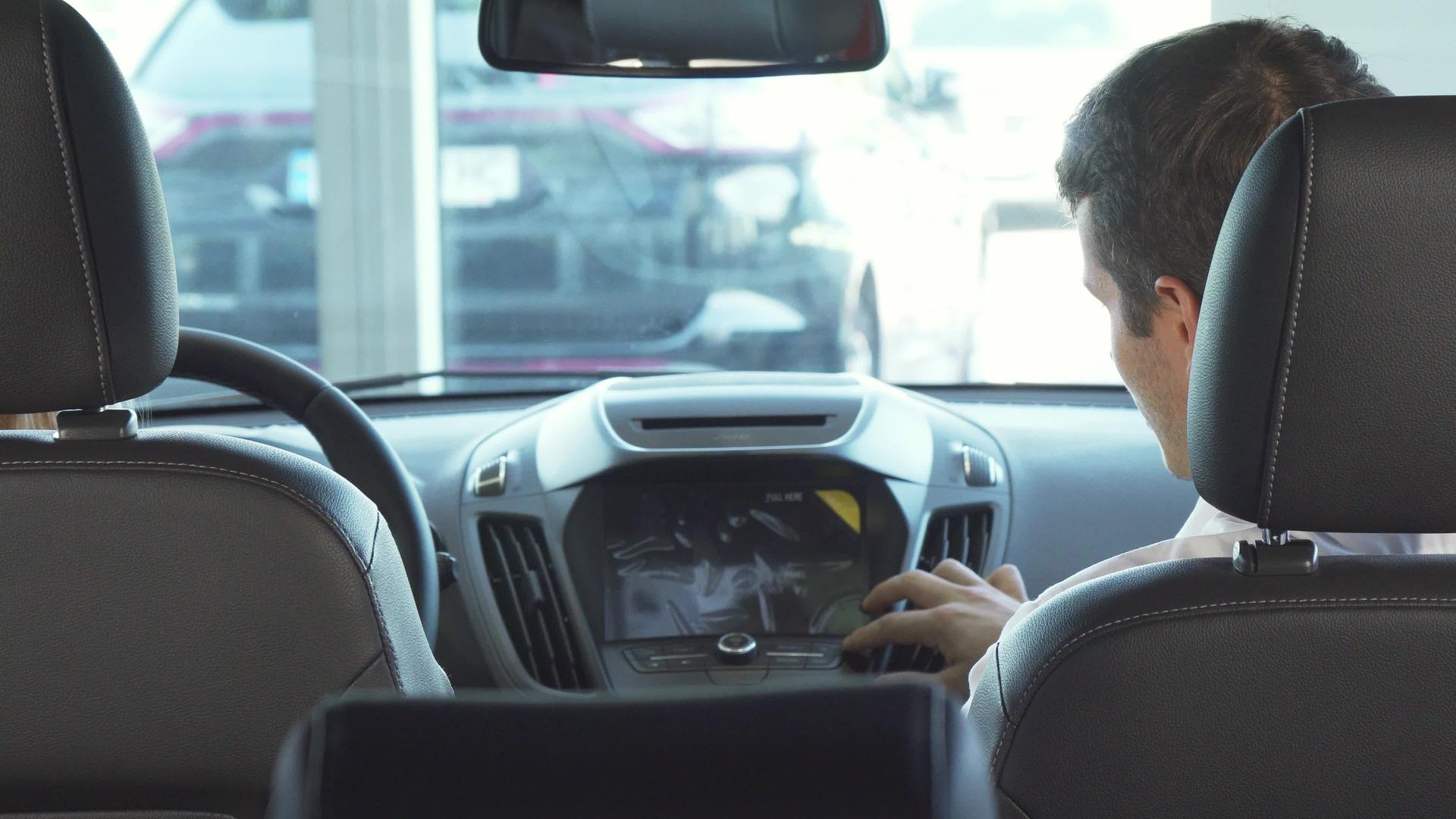 父亲和女儿微笑着坐在前排座位上看着汽车的小屏幕视频的预览图
