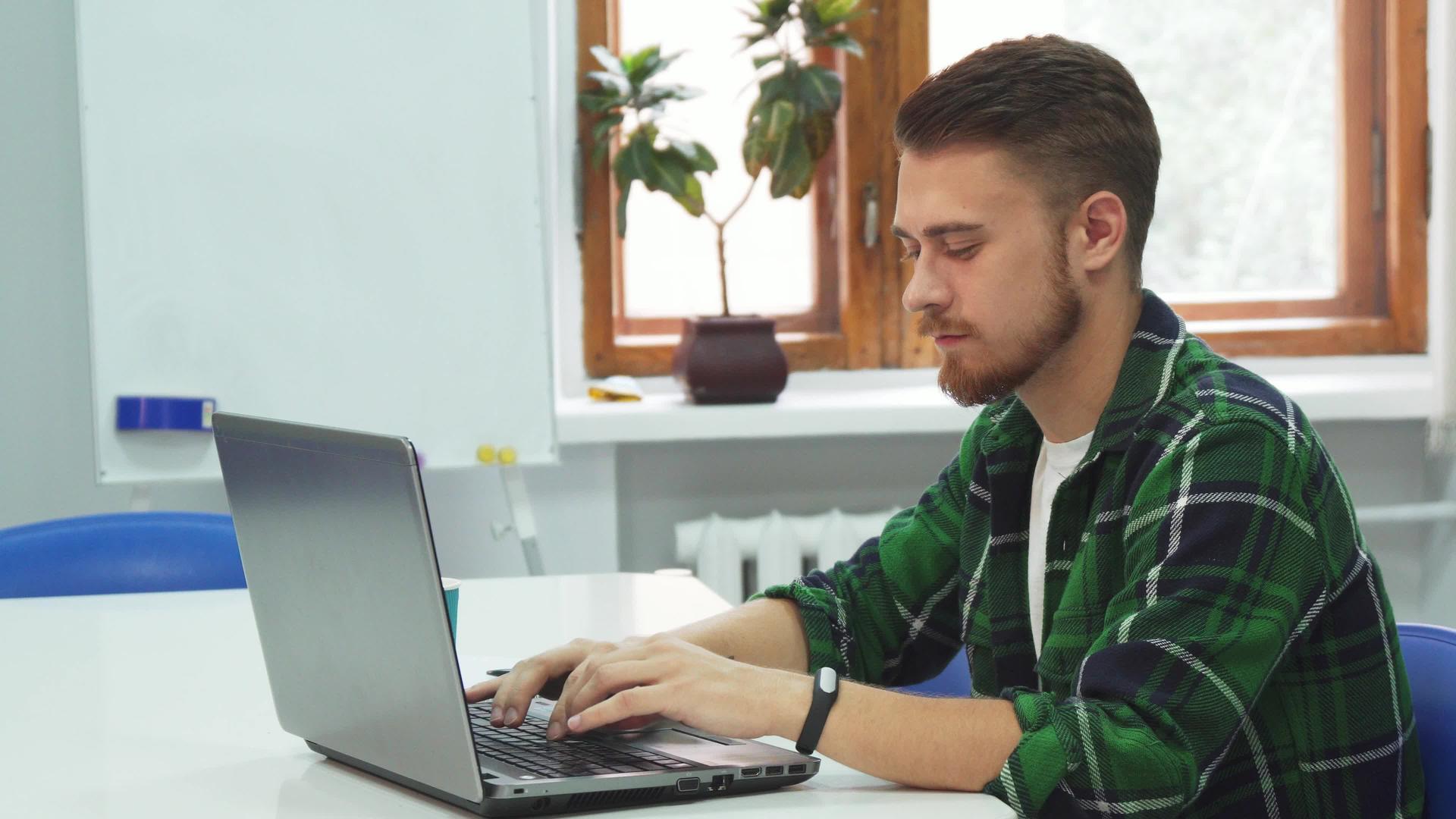 一个年轻人坐在教育机构的电脑前视频的预览图