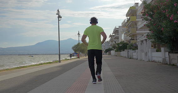 拿着耳机的年轻人在城市里奔跑Pereagreeece路上视频的预览图