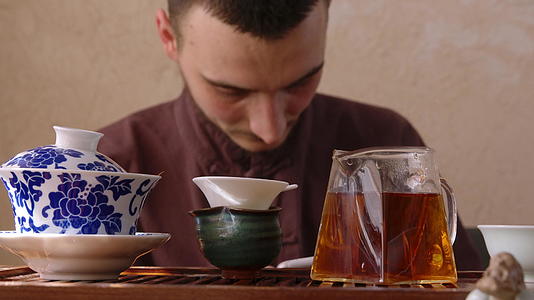 年轻人在东方餐厅喝茶时通过智能手机在茶几上使用手机大师视频的预览图